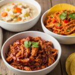 A variety of easy shredded chicken recipes including BBQ chicken, chicken taco filling, and creamy soup, presented in bowls on a rustic table