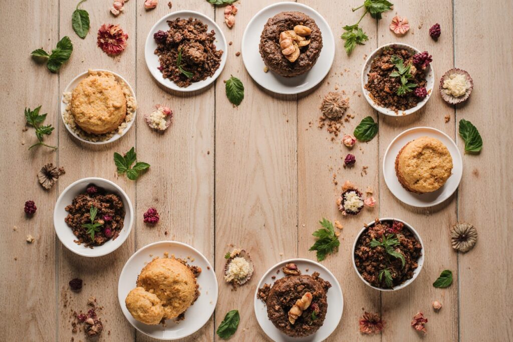 Colorful assortment of healthy desserts including avocado chocolate mousse, energy balls, and chia pudding arranged on a rustic wooden table