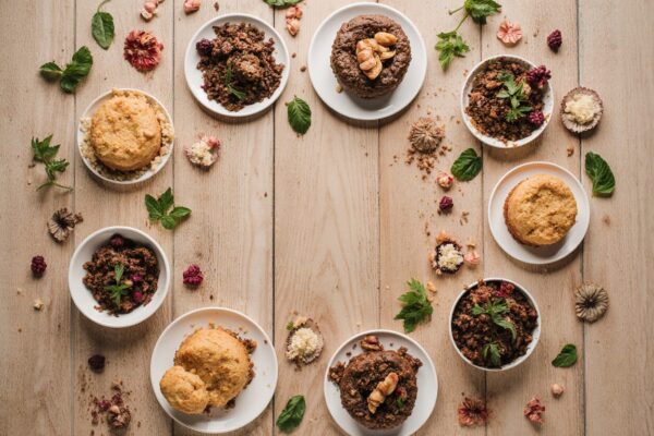 Colorful assortment of healthy desserts including avocado chocolate mousse, energy balls, and chia pudding arranged on a rustic wooden table
