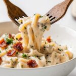 Creamy chicken bacon ranch pasta in a white bowl, garnished with fresh parsley and extra bacon crumbles