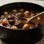 Hearty beef stew in a Dutch oven with tender meat, carrots, and potatoes in rich gravy