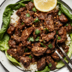 Sizzling Korean beef in a cast-iron skillet with sesame seeds and green onions, served with steamed rice