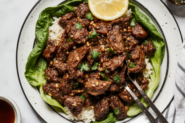 Sizzling Korean beef in a cast-iron skillet with sesame seeds and green onions, served with steamed rice