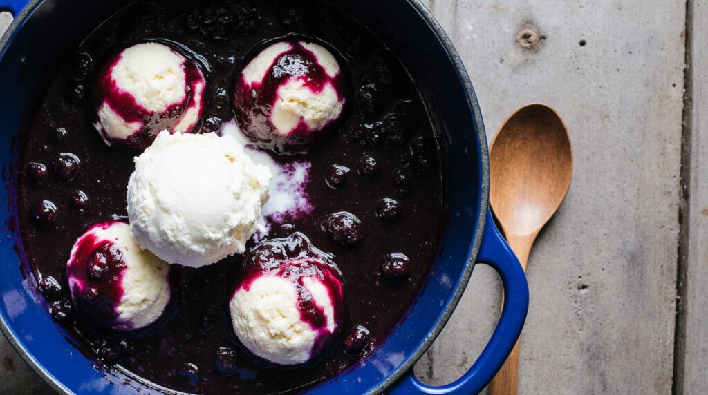 Steaming bowl of Blueberry Grunt with juicy berries and fluffy dumplings, dusted with powdered sugar