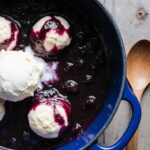 Steaming bowl of Blueberry Grunt with juicy berries and fluffy dumplings, dusted with powdered sugar