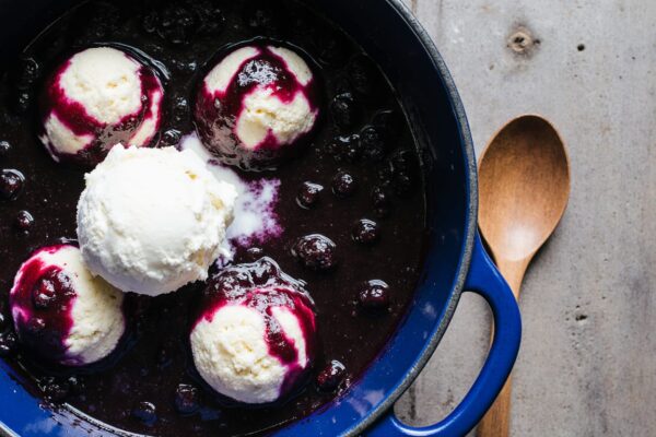 Steaming bowl of Blueberry Grunt with juicy berries and fluffy dumplings, dusted with powdered sugar