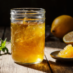 A jar of vibrant homemade lemon jam with visible zest, photographed in warm natural light to showcase its glossy, inviting texture.
