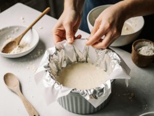 Securing the foil cover on a pudding basin before steaming, a key step in Steamed Sponge Pudding preparation.
