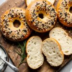 Freshly baked golden brown cottage cheese bagels with everything seasoning, sliced open to show soft interior, served with cream cheese.