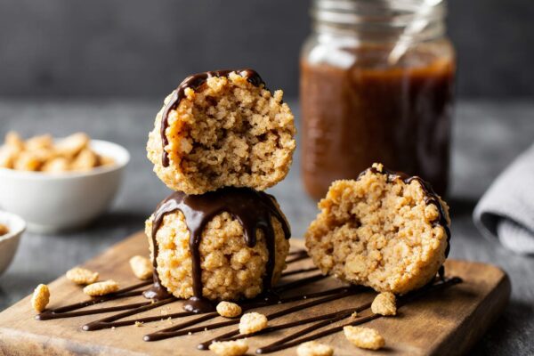 A tempting stack of homemade peanut butter Rice Krispie balls with chocolate drizzle, the ultimate easy no-bake treat.