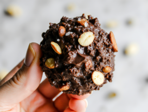 A close-up of a hand holding a perfect quinoa chocolate cluster, showcasing the crunchy texture and dark chocolate coating.