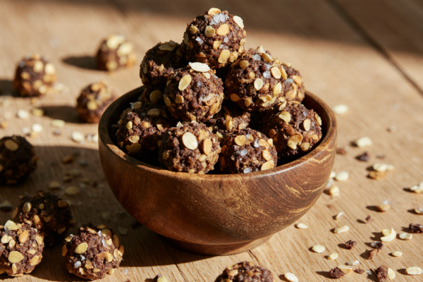 A rustic wooden bowl filled with homemade quinoa chocolate clusters, featuring crunchy quinoa, dark chocolate, almonds, and pumpkin seeds.